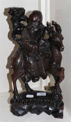 Lot 163 - A Chinese white metal inlaid hardwood carving of a sage astride a deer, on a naturalistic base