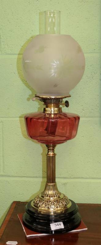 Lot 344 - A brass oil lamp, late 19th century, with etched globe ruby glass reservoir and fluted column...