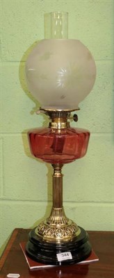 Lot 344 - A brass oil lamp, late 19th century, with etched globe ruby glass reservoir and fluted column...