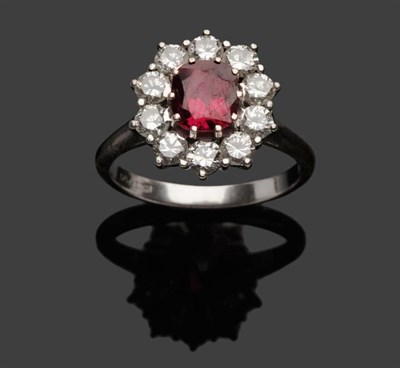 Lot 613 - A Ruby and Diamond Cluster Ring, an oval cut ruby within a border of ten round brilliant cut...