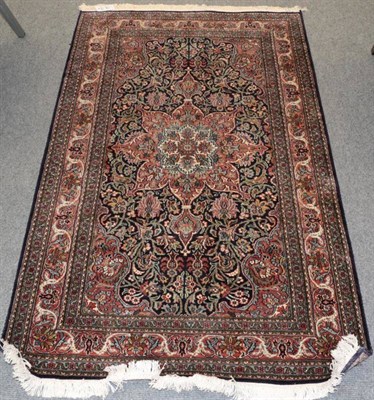 Lot 1393 - A Kashmir silk piled rug, the indigo filed of vines centred by a flowerhead medallion, framed...