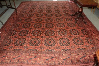 Lot 1396 - A large Afghan carpet, the terracotta field with rows of guls, enclosed by multiple borders,...