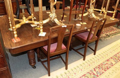 Lot 1472 - An early 20th century oak wind out dining table, with four leaves and four chairs