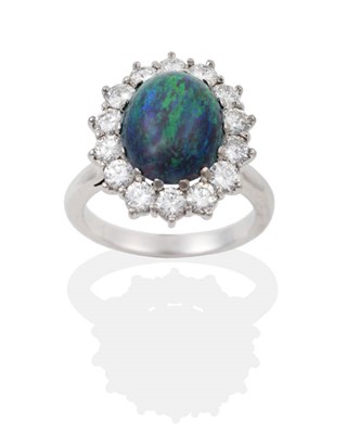 Lot 57 - A Black Opal and Diamond Cluster Ring, the oval cabochon opal within a border of fourteen round...