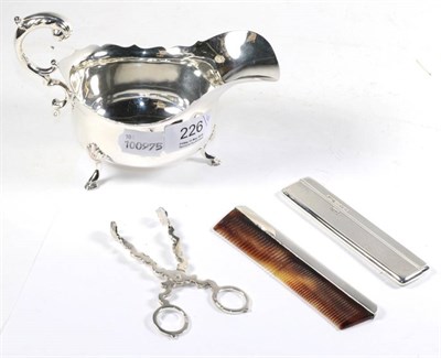 Lot 226 - A silver sauce boat, two silver combs and a pair of silver sugar tongs (4)