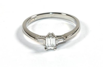 Lot 273 - A platinum solitaire octagonal cut diamond ring, in a claw setting, to tapered baguette cut diamond