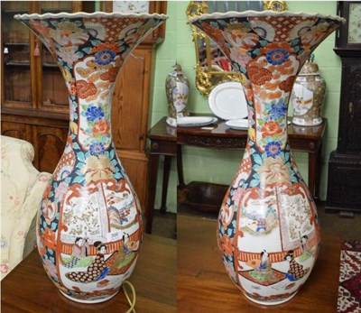 Lot 398 - A pair of Japanese floor standing vases with everted rims and decorated with figures and pagodas