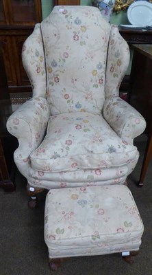 Lot 1276 - A 1950s Epstein wing back armchair with floral upholstery and matching footstool