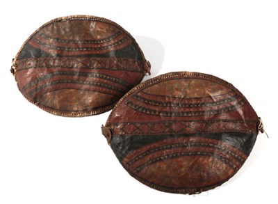 Lot 301 - Two Masai Hide Shields, each of elliptical form, painted with curved bands of diapering and...