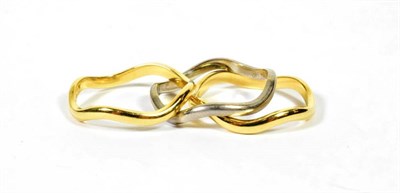 Lot 99 - An 18 carat gold triple band stacking ring, comprising a central matt polished white gold wavy band