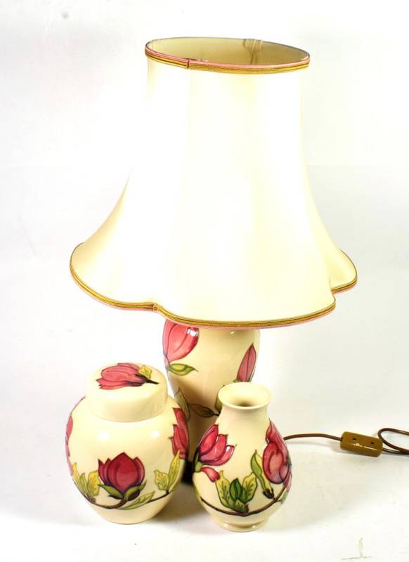 Lot 150 - A Moorcroft pottery Magnolia pattern table lamp on a cream ground together with a vase and...