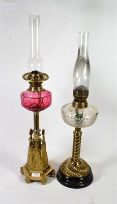 Lot 209 - A Victorian brass oil lamp with castellated base and cranberry shade; together with another oil...