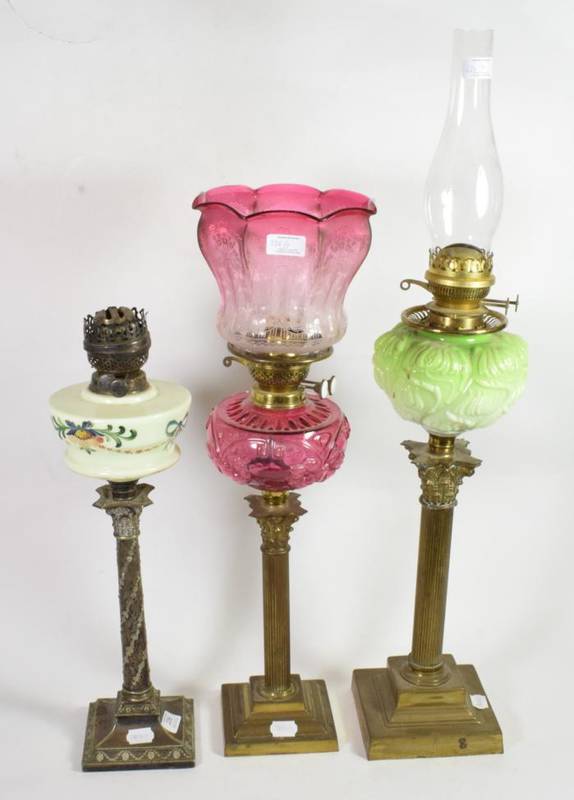 Lot 226 - Three 19th century oil lamps, each on columnar bases and with glass reservoirs, one with a...