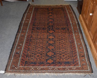 Lot 1181 - A Balouch rug, the chestnut field with columns of geometric motifs enclosed by narrow borders,...