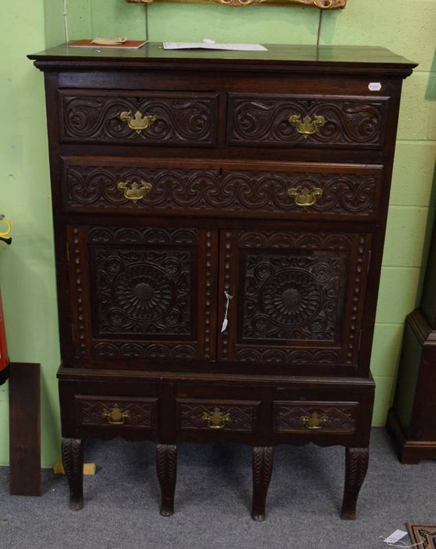 Lot 1201 - A carved oak chest on stand, the upper section with two short above one long drawer with two...