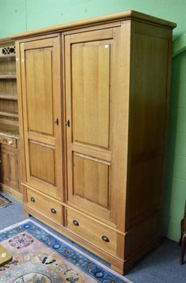 Lot 1294 - An oak double wardrobe fitted with base drawers