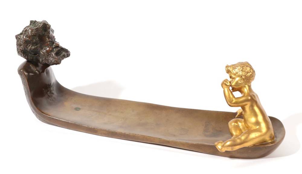 Lot 547 - A French Art Nouveau Patinated and Gilded Bronze Pen Tray, cast with the head of an old man blowing
