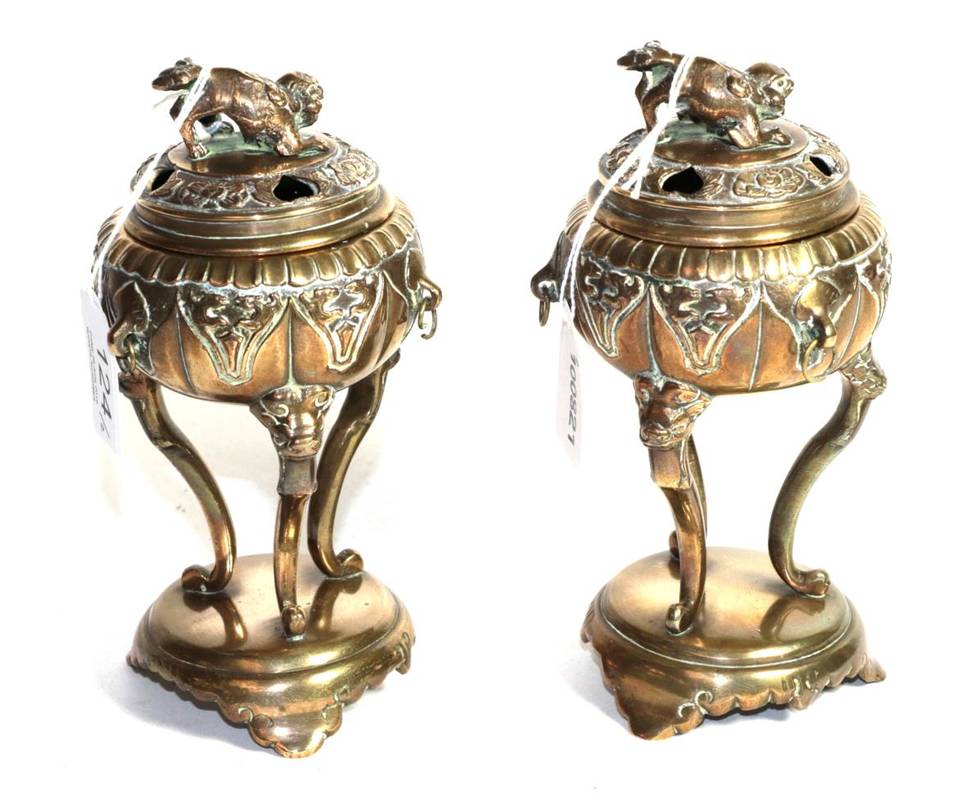 Lot 124 - A pair of Chinese brass tripod censers and covers, surmounted by temple lions integral plinths...
