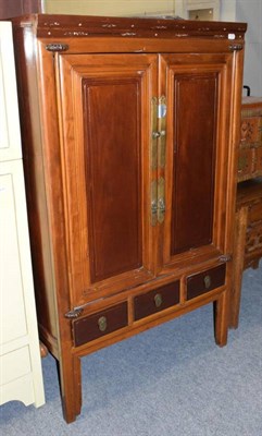 Lot 1178 - A Chinese cupboard, 20th century, with a pair of cupboard doors over three short drawers