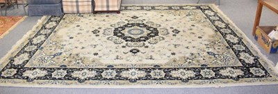 Lot 1223 - A machine made carpet of Kashan design, the ivory field centred by an indigo medallion, framed...