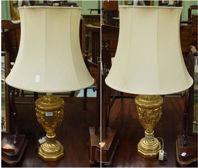 Lot 1280 - A pair of reproduction gilt plaster table lamps in the Neo-classical taste, with silk shades