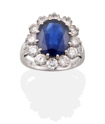 Lot 6 - An 18 Carat White Gold Sapphire and Diamond Cluster Ring, an oval mixed cut sapphire in a claw...