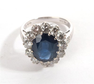 Lot 6 - An 18 Carat White Gold Sapphire and Diamond Cluster Ring, an oval mixed cut sapphire in a claw...