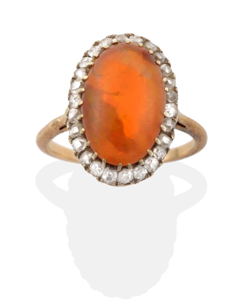 Lot 12 - A Fire Opal and Diamond Cluster Ring, an oval cabochon fire opal within a border of old cut...