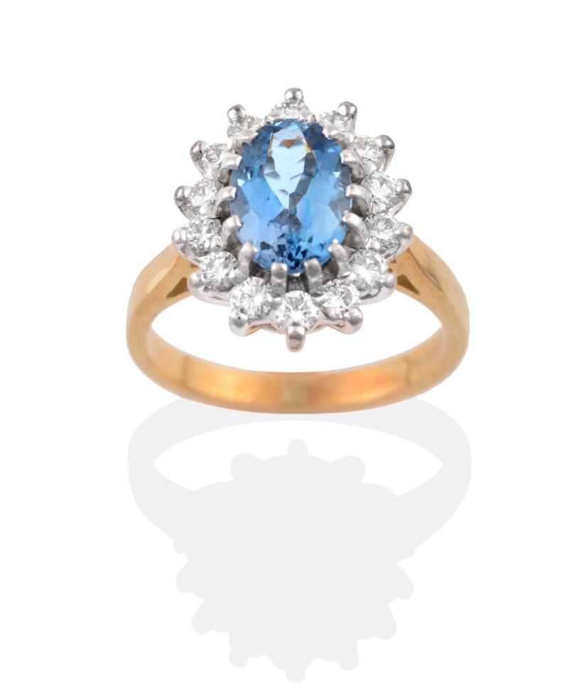 Lot 33 - An 18 Carat Gold Aquamarine and Diamond Cluster Ring, an oval cut aquamarine within a border of...
