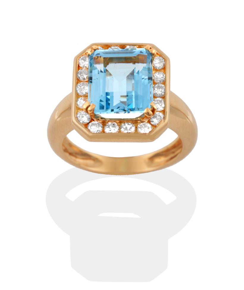 Lot 34 - An Aquamarine and Diamond Cluster Ring, an emerald-cut aquamarine in a yellow four claw...