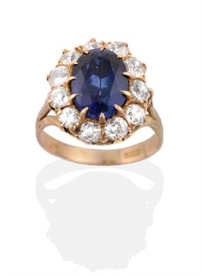 Lot 35 - A Synthetic Sapphire and Diamond Cluster Ring, an oval cut synthetic sapphire in a claw...