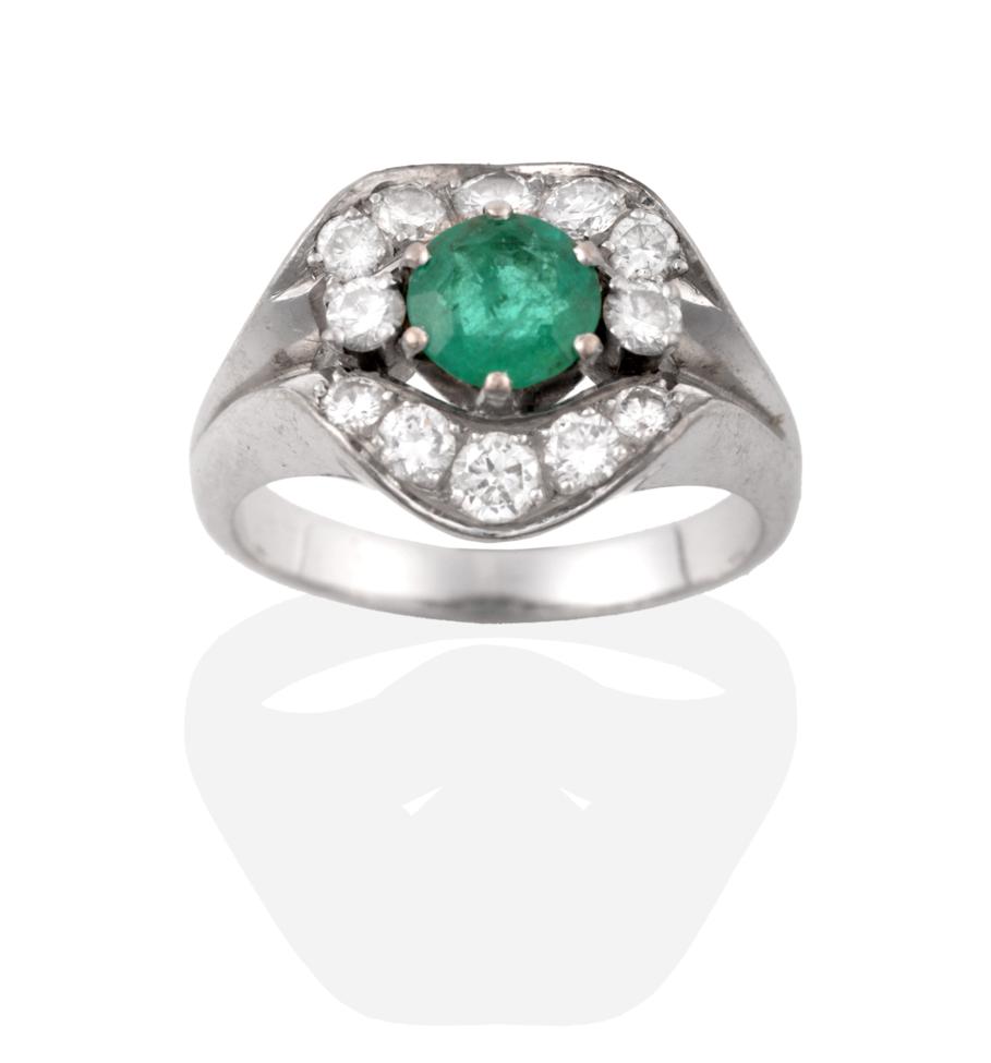 Lot 47 - A Contemporary Emerald and Diamond Cluster Ring, a round cut emerald flanked by two round brilliant