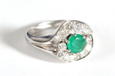 Lot 47 - A Contemporary Emerald and Diamond Cluster Ring, a round cut emerald flanked by two round brilliant