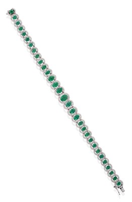 Lot 51 - An 18 Carat White Gold Emerald and Diamond Cluster Bracelet, thirty one graduated oval cut emeralds