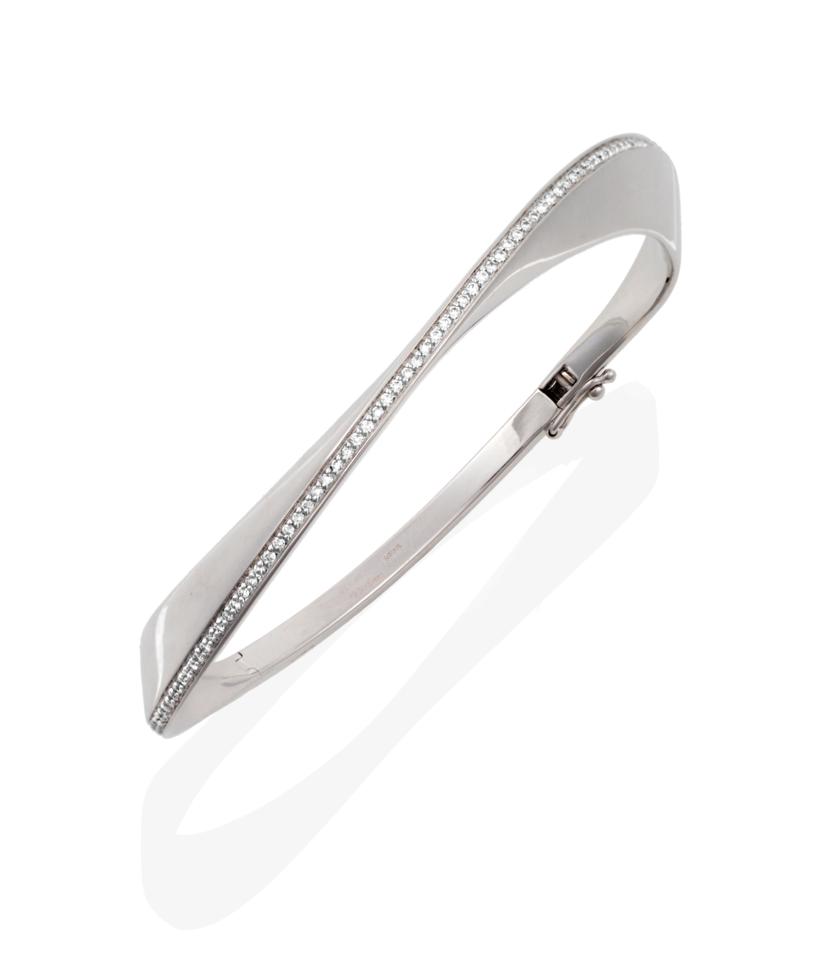 Lot 63 - An 18 Carat White Gold Diamond Set Bangle, in a twisting form, with a line of round brilliant...