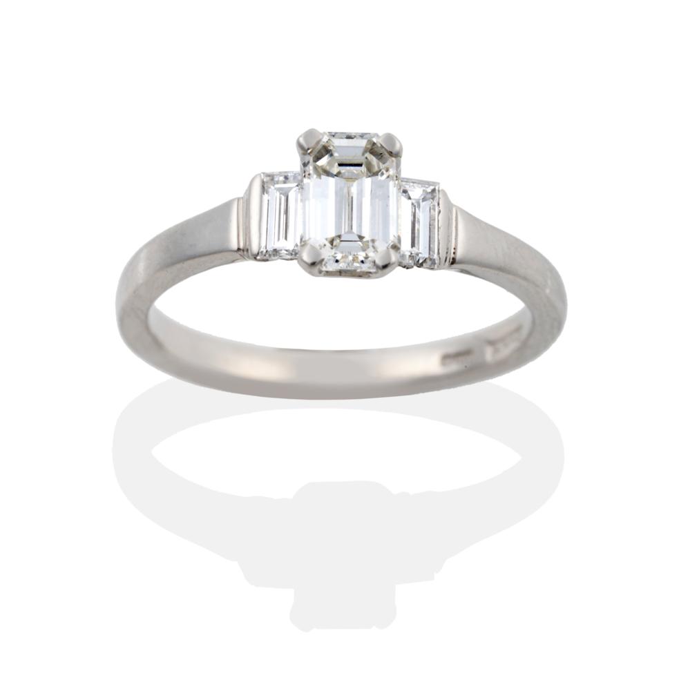 Lot 74 - A Platinum Diamond Three Stone Ring, a central emerald-cut diamond in a four claw setting,...