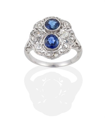 Lot 85 - A Sapphire and Diamond Cluster Ring, two round mixed cut sapphires in white rubbed over...