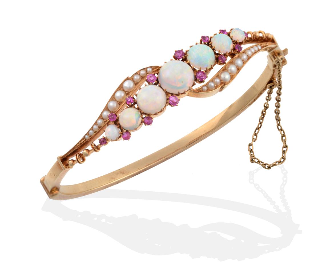 Lot 121 - An Opal, Ruby and Seed Pearl Bangle, graduated round cabochon opals spaced by pairs of round...