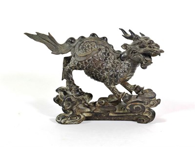 Lot 583 - A Chinese Bronze Figure of a Kylin, Qing Dynasty, standing four-square on a stylised wave and...