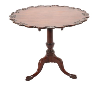 Lot 735 - A Carved Mahogany Tripod Table, in George III style, the fliptop with a carved C scroll border,...