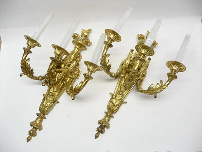 Lot 1195 - A Pair of Gilt Metal Three-Branch Wall Appliqués, 20th century, with flammiform and fluted...