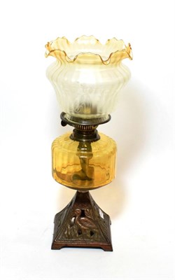 Lot 159 - ^ A late Victorian oil lamp with yellow tinted glass reservoir, the metal base in the form of...