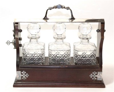 Lot 279 - An electroplated mounted three bottle tantalus, with three square section decanters, with key