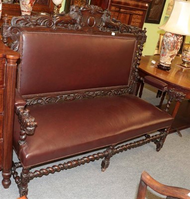 Lot 1363 - ^ A late Victorian carved oak hall seat, upholstered in close nailed leather, with carved hand...