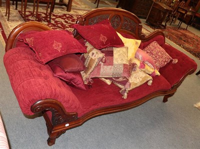 Lot 1385 - ^ A Victorian walnut framed scroll end sofa, recovered in red buttoned fabric, the verso...