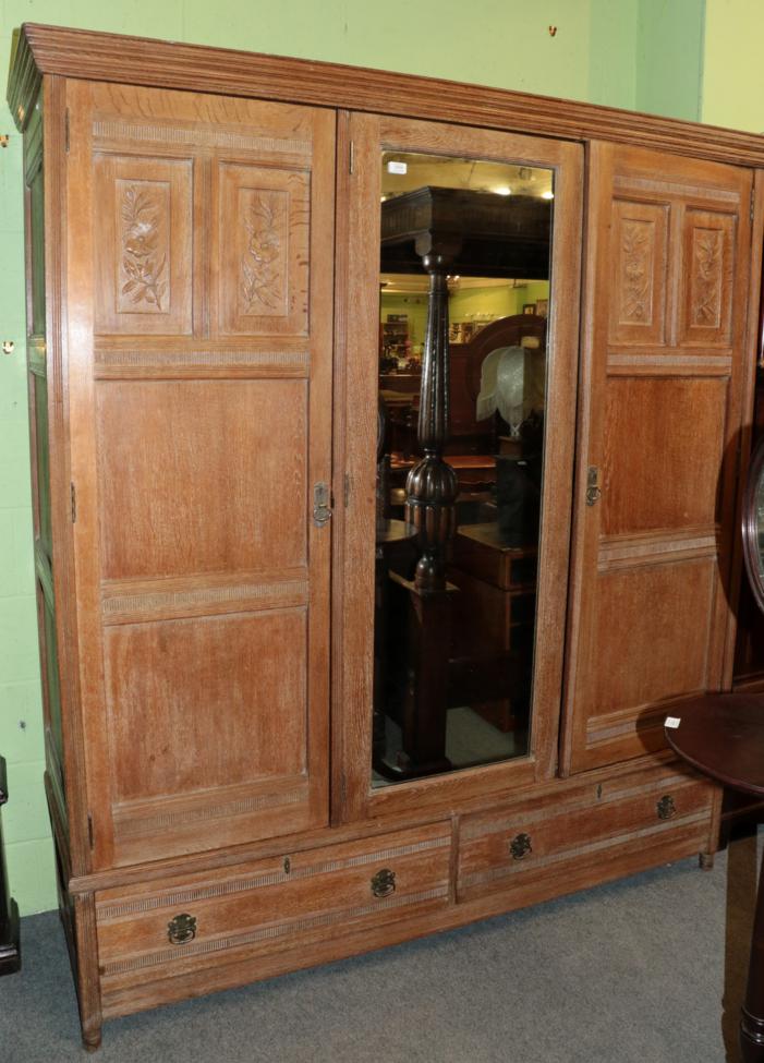 Lot 1434 - An Arts & Crafts Limed Oak Wardrobe, designed by Frederick Muntzer, three-door two-sectional...