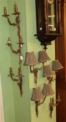 Lot 1458 - A set of seven gilt metal decorative twin light wall lights with shades decorated with acorns...