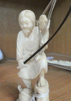 Lot 222 - A Japanese ivory okimono, Meiji period (1868-1912) in the form of a fisherman holding a wooden...