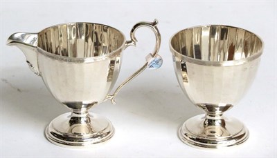 Lot 239 - A George V silver cream-jug and sugar-bowl, by Adie Brothers, Birmingham, 1928, each piece facetted