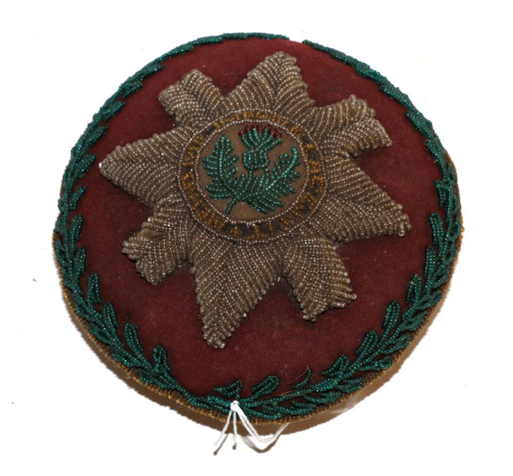 Lot 317 - An early 20th century beadwork pin cushion to the Scots Guards, of circular form, worked with...
